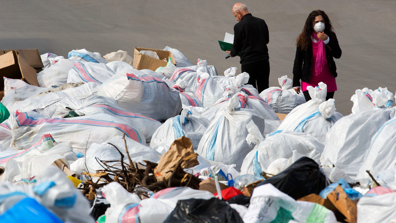 A Lebanese woman covers her mouth with a medical mask as she passes by a pile of garbage on a street in Beirut, Lebanon, Friday, March 4, 2016. Photo: Hassan Ammar/AP.